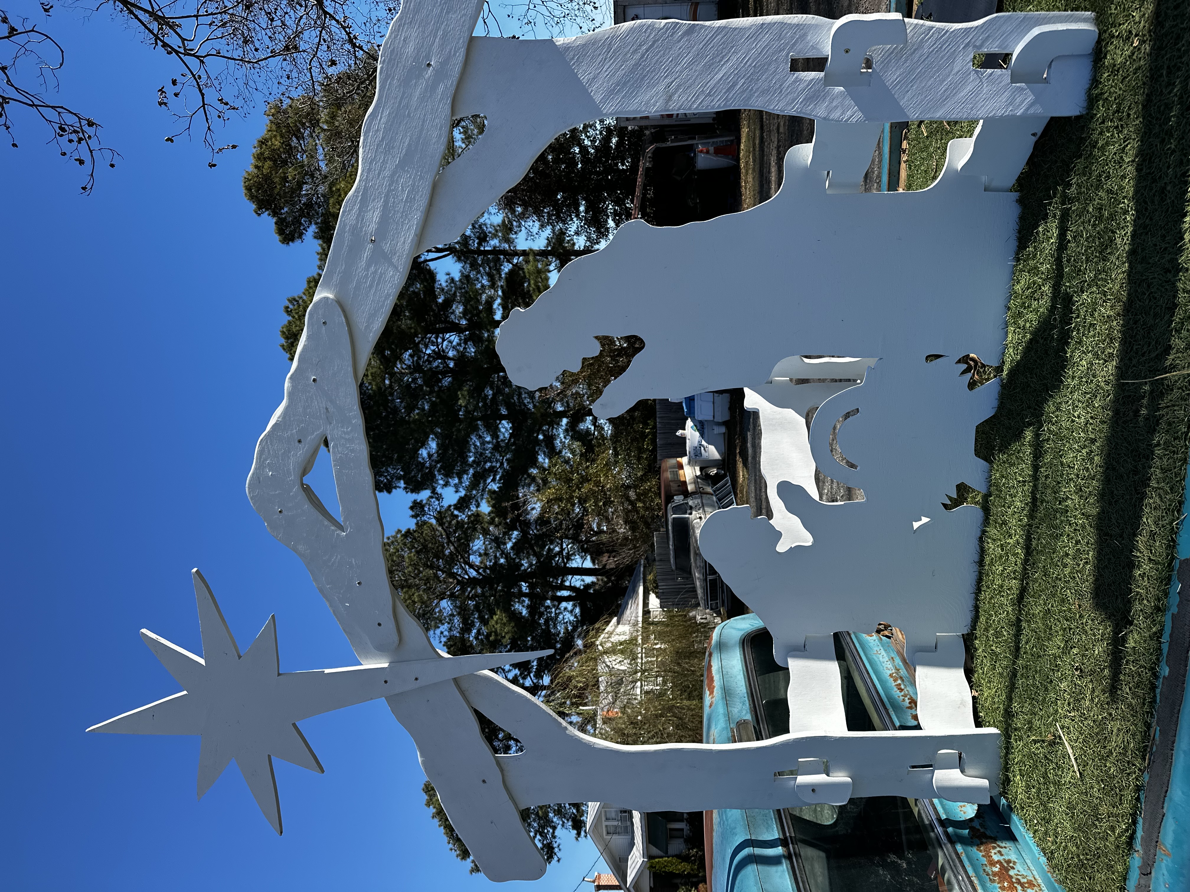 A 6ft Nativity sits on outdoor carpet in the bed of an old pickup truck. The nativity is 3d and painted white.